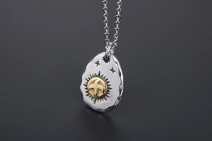 Macro shot of vintage titanium steel eagle pendant with gold sun motif and cross chain