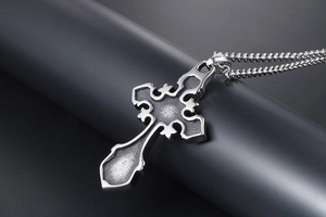 Macro detail of Gothic cross pendant with vintage silver engraving on a ball chain