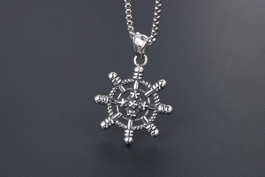 Vue macro du pendentif gouvernail argenté avec motifs d'étoiles et texture nautique