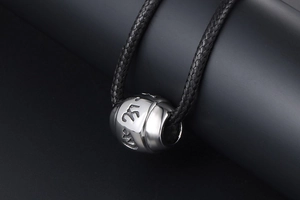 Macro detail of titanium steel mantra bead pendant with engraved religious symbols