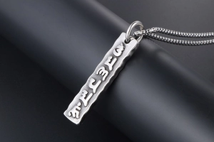 Close-up of hammered titanium steel pendant necklace featuring ancient sanskrit relief
