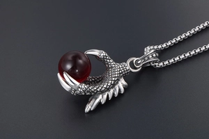 Macro detail of Gothic eagle claw pendant holding a dark red gemstone on a box chain