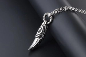 Close-up of vintage steel wolf tooth pendant with flame relief on black display