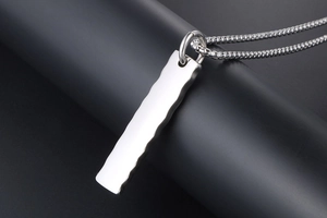 Detailed view of silver titanium pendant with wavy textures on a dark display stand