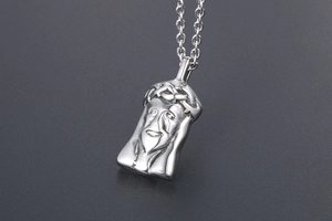 Macro detail of relief Jesus face pendant and crown of thorns in vintage titanium steel