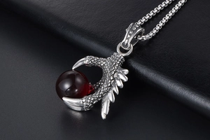 Detailed close-up of a silver dragon claw pendant holding a deep red gemstone bead