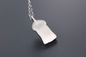 Macro view of silver stainless steel pendant featuring a brushed metal back finish