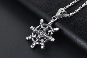 Gros plan du pendentif gouvernail argenté avec étoile sur fond en cuir noir texturé