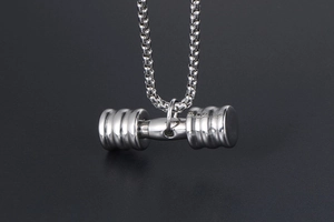 Détail d'un pendentif haltère argenté poli sur une chaîne perle avec texture industrielle