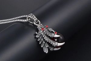 Detail of silver eagle claw pendant holding a dark red gemstone with vintage texture