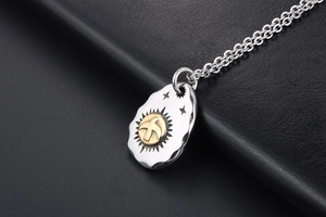 Macro shot of two-tone eagle pendant with sunburst texture on black leather background