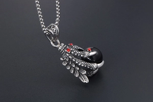 Detailed view of silver dragon claw pendant holding a black bead with red stones