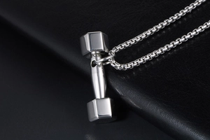 Gros plan du pendentif haltère en argent avec chaîne maille box sur fond de cuir noir