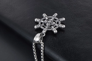 Gros plan détaillé du pendentif gouvernail rétro sur chaîne box sur fond cuir noir
