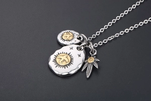 Detailed close-up of eagle pendants and leaf charm on a titanium steel necklace chain