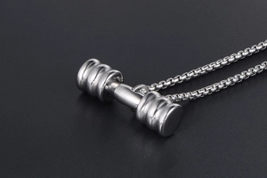 Détail macro du pendentif haltère argenté poli avec des disques de poids bien texturés