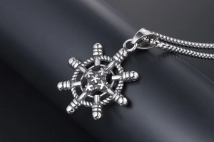 Vue macro d'un pendentif gouvernail vintage avec chaîne tressée sur support gris foncé