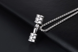 Vue rapprochée d'un collier pendentif haltère en métal poli sur fond de cuir élégant