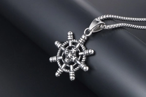 Gros plan sur un pendentif gouvernail rétro avec étoiles en relief et fini argent antique