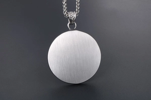 Detail of vintage silver titanium pendant with brushed texture and ornate scroll bail