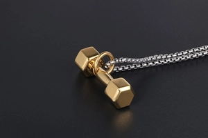 Macro d'un pendentif haltère doré avec chaîne box argentée pour sportifs