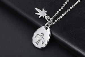 Detail shot of vintage stainless steel eagle pendant with leaf charm on black leather background