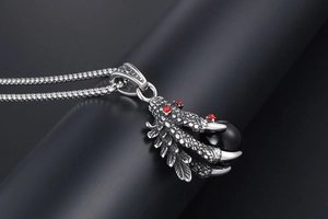 Macro shot of silver dragon claw necklace holding a black bead with red rhinestones