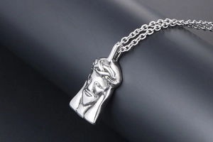 Close-up of polished silver titanium steel Jesus head pendant and cross chain detail