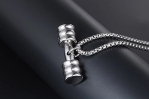Gros plan détaillé d'un pendentif haltère en argent avec texture métallique et jeux d'ombre