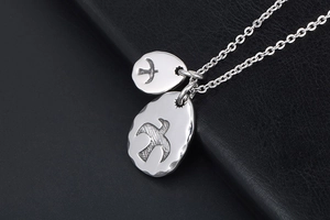 Macro shot of silver eagle pendants on black leather with vintage sunburst engravings