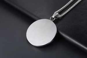 Macro shot of silver brushed metal pendant on a premium black leather texture background