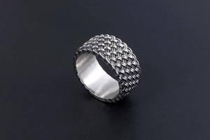 Close-up of wide silver titanium steel ring with intricate woven mesh pattern texture