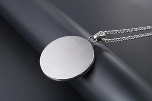 Macro detail of a brushed silver titanium steel pendant with a subtle flame texture