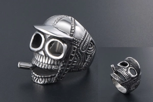 Macro detail of vintage silver skull ring wearing a cap and smoking a cigarette