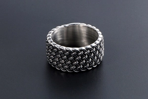 Close-up of wide titanium steel ring with vintage braided mesh texture and silver finish