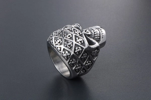 Macro view of punk skull ring featuring fleur-de-lis carvings and vintage steel finish
