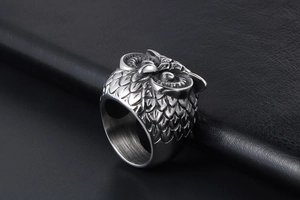 Detailed close-up of a vintage owl ring with gothic feather textures on black leather