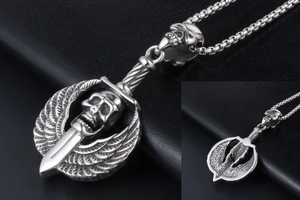 Close-up of vintage punk skull and wing pendant with gothic dagger in aged silver finish