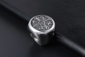 Close-up of retro titanium steel signet ring with engraved cross symbol on black leather