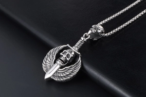 Macro shot of punk style skull pendant with wings and sword on black leather
