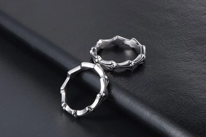 Detail view of silver gothic spike titanium steel rings on black leather texture
