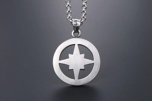 Detail of brushed titanium steel round pendant with hollow four-pointed star pattern