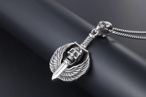 Macro shot of punk skull sword pendant with feathered wings in distressed silver steel