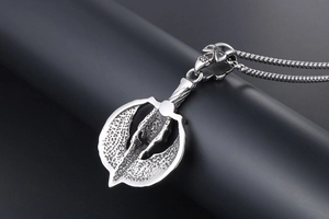 Macro detail of gothic skull pendant necklace with silver wing texture on box chain