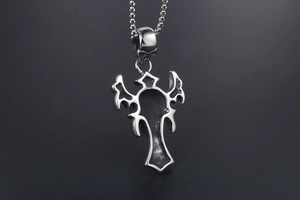 Close-up of gothic cross pendant with detailed wings and skull on steel bead chain