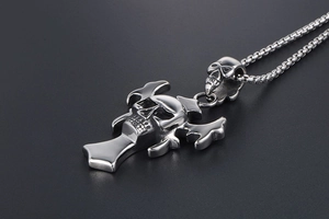 Macro shot of silver punk skull pendant with bat wings and cross on box chain necklace