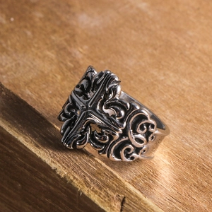 Retro titanium steel cross ring with intricate baroque floral engravings on wood background
