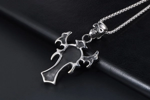 Close-up of vintage skull and cross pendant with box chain on black leather background