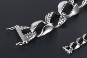 Macro detail of silver Cuban chain bracelet with textured crocodile pattern links