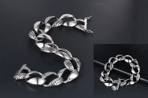 Macro detail of men's chunky silver snake pattern chain bracelet with textured scales
